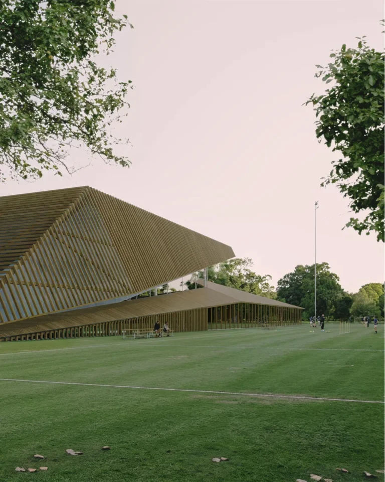 Architectural visualisation of a sports center building with a grass pitch in front