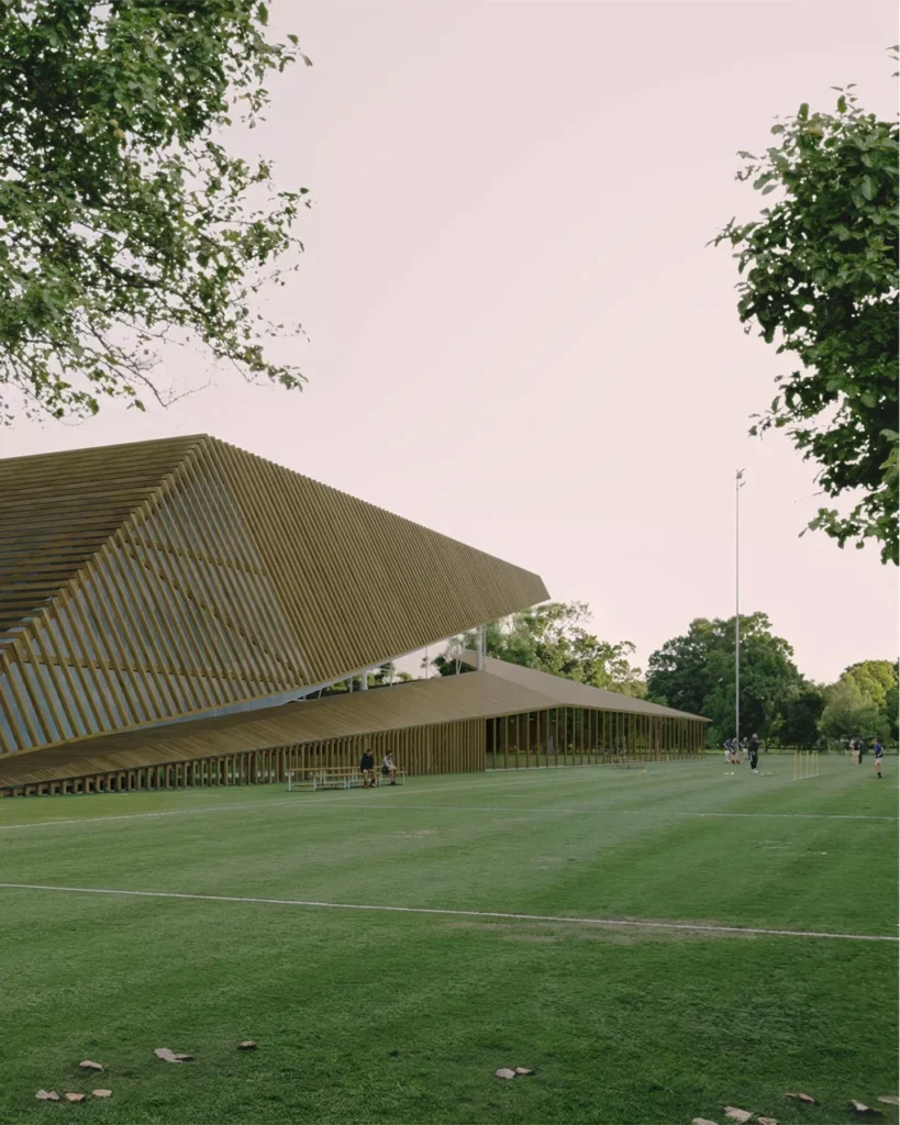 Architectural visualisation of a sports center building with a grass pitch in front
